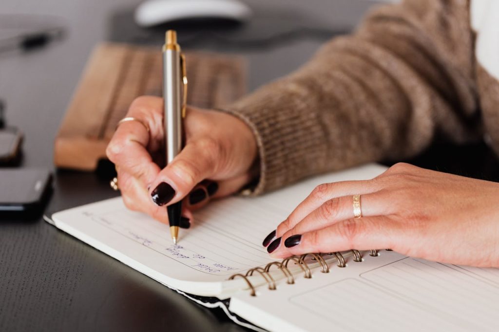 A woman writing notes in a notepad.