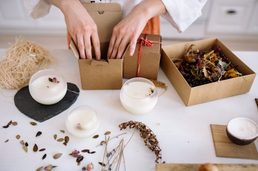 Creating Attractive Product Bundles A person packing candles in cardboard boxes as a bundle.