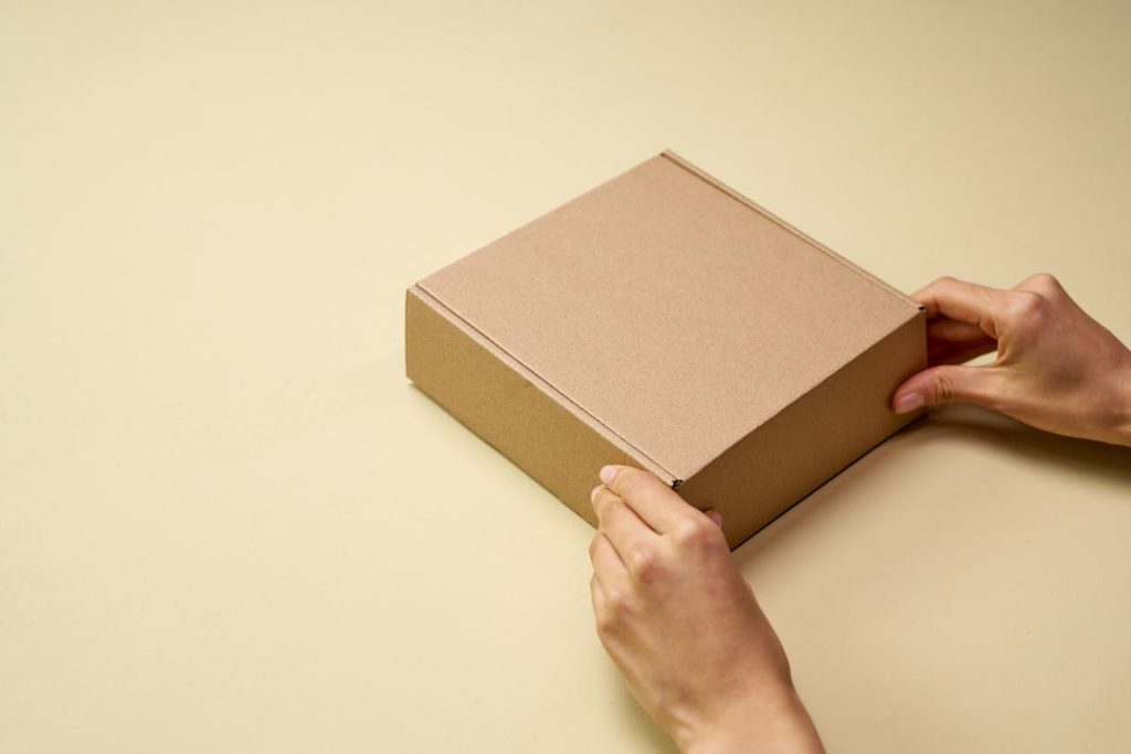 Enhancing Customer Experience with Free Shipping A person folding a shipping box containing an item.