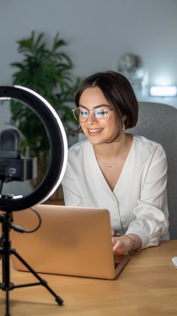 Freelancer recording a video at a clean desk setup, showing confidence and personal touch, with warm lighting and a ring light.